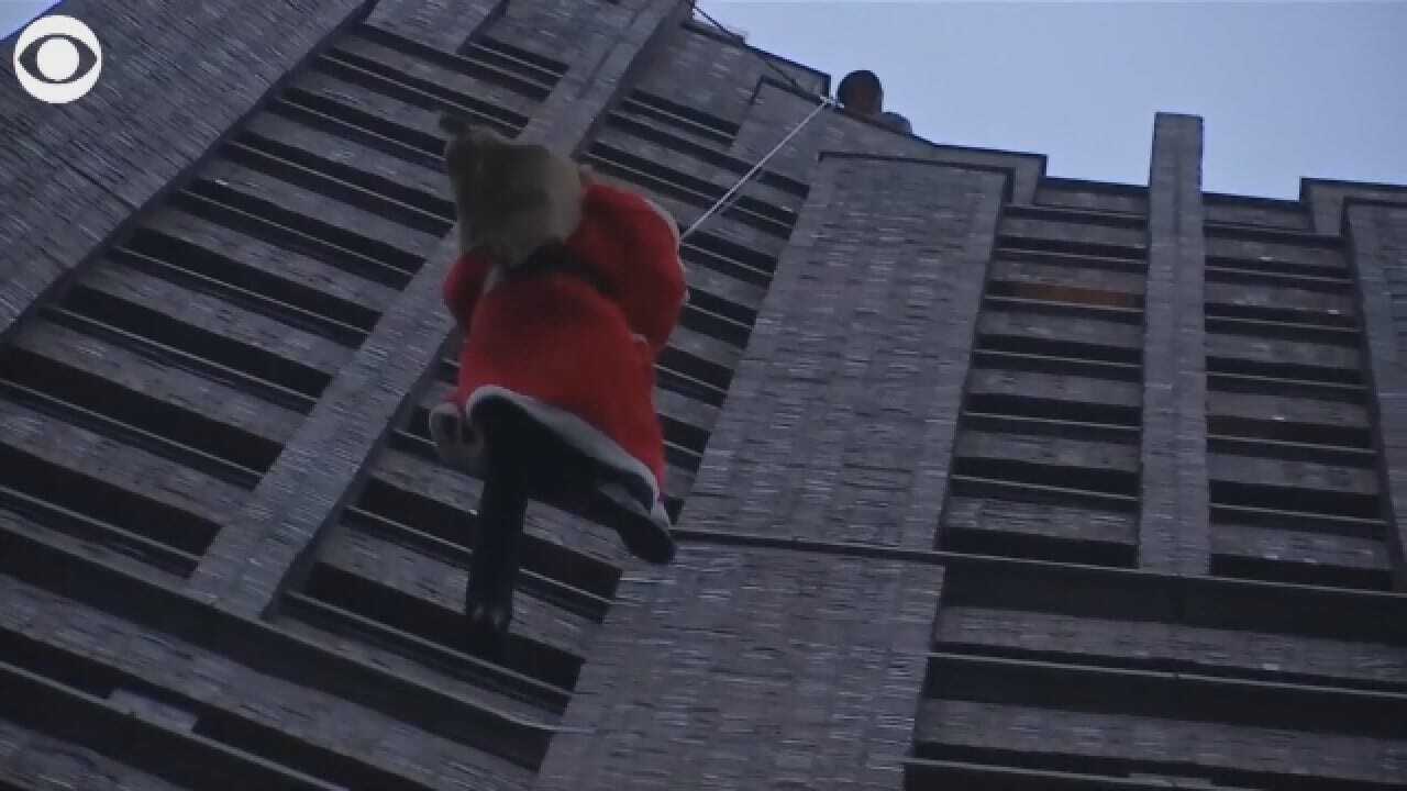 Children Watch As Santa Rappels Down From A High-Rise Building